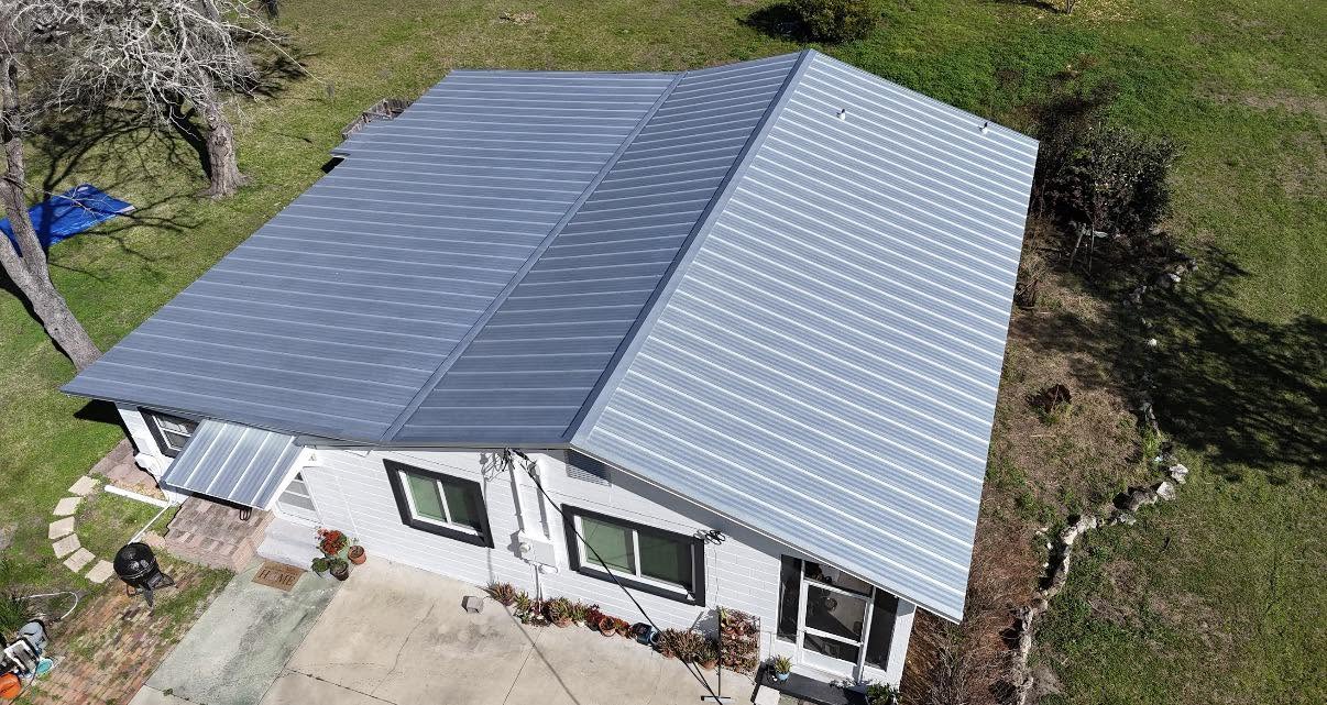 A finished standing seam metal roof in a light grey profile