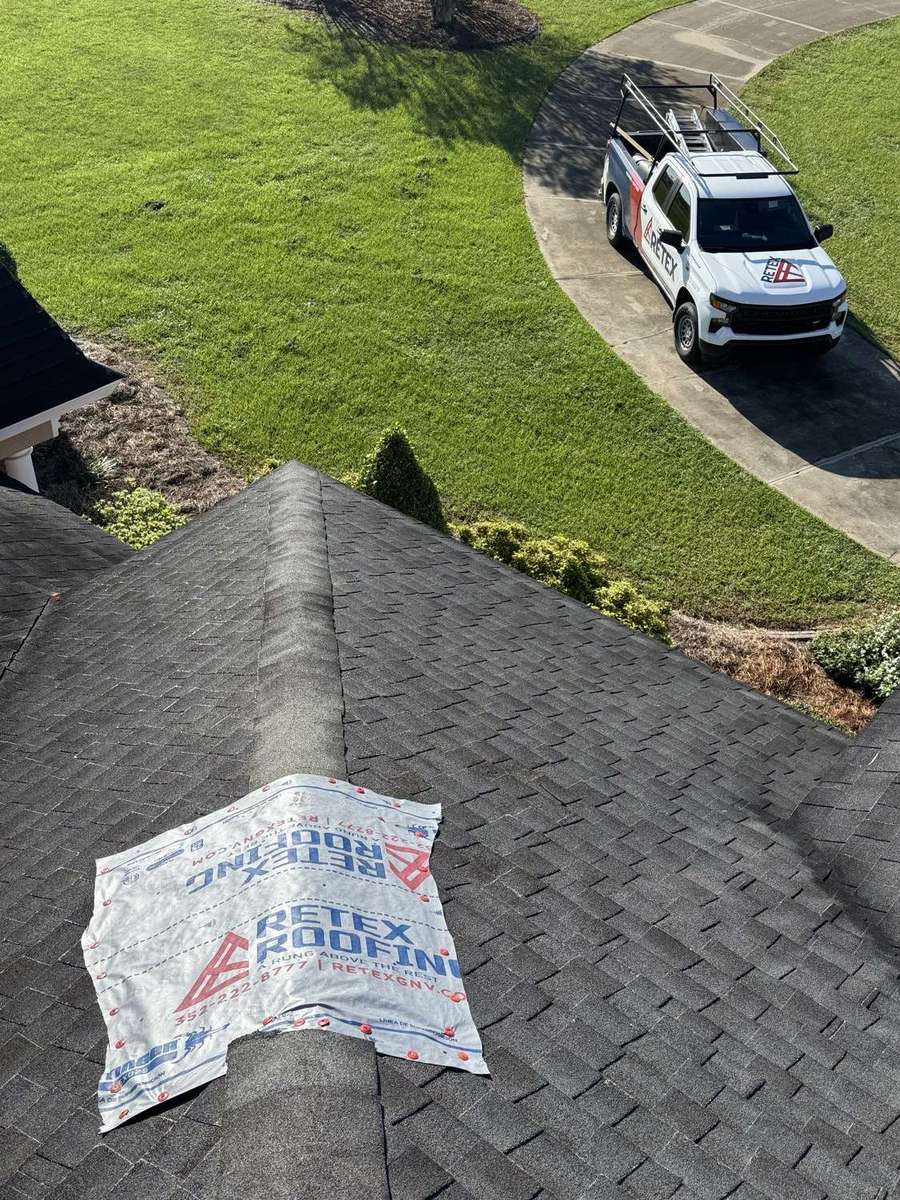 A Retex Roofing truck in the driveway of a completed shingle roof