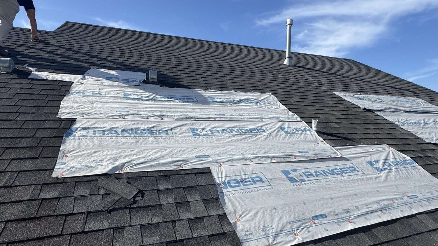 Pro-grade synthetic underlayment being installed on a roof deck