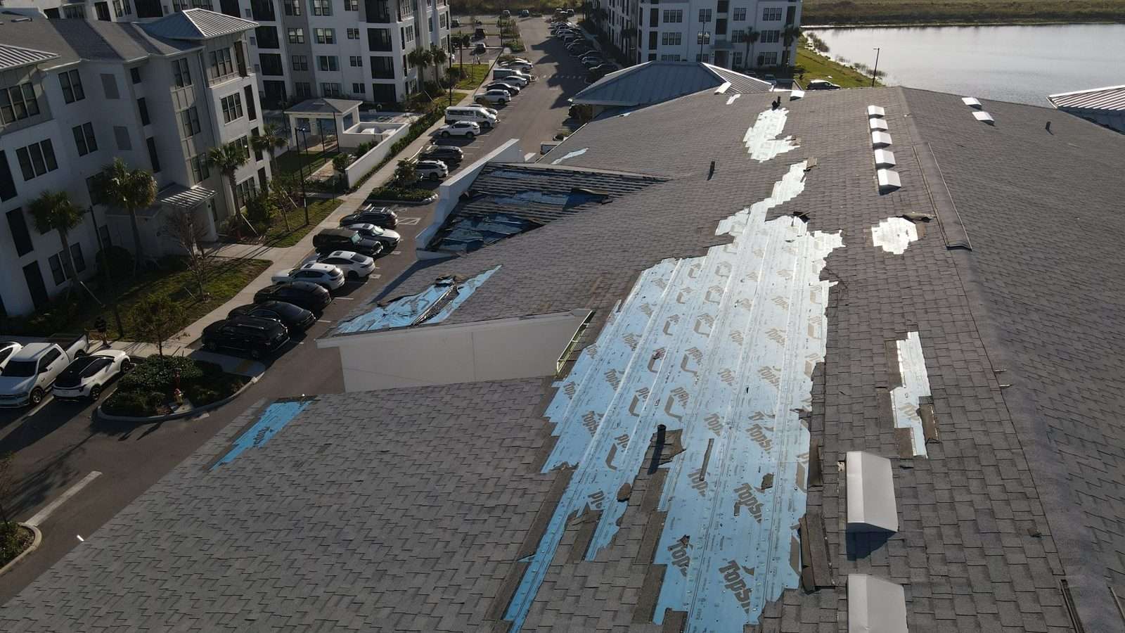 A roof with a large torn-open section exposing the synthetic underlayment beneath